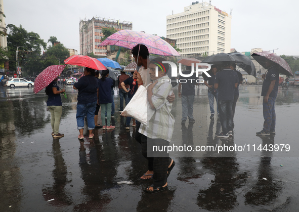 A man is holding an umbrella as he is crossing a road during monsoon rain in Kolkata, eastern India, on July 30, 2024 