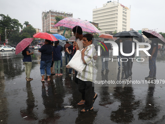 A man is holding an umbrella as he is crossing a road during monsoon rain in Kolkata, eastern India, on July 30, 2024 (