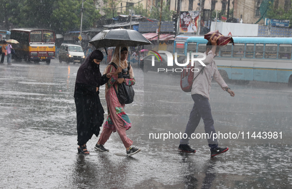 Commuters are crossing a road during heavy monsoon rain in Kolkata, eastern India, on July 30, 2024 