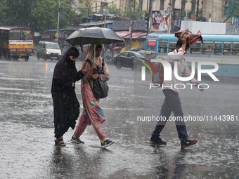 Commuters are crossing a road during heavy monsoon rain in Kolkata, eastern India, on July 30, 2024 (