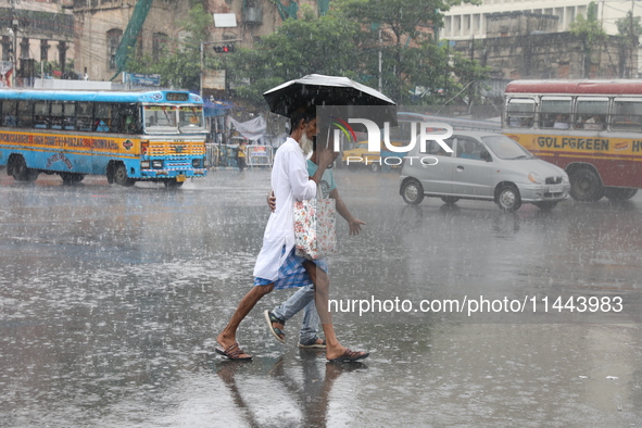 Men are crossing a road during heavy monsoon rain in Kolkata, India, on July 30, 2024. 