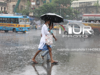 Men are crossing a road during heavy monsoon rain in Kolkata, India, on July 30, 2024. (