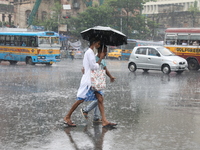 Men are crossing a road during heavy monsoon rain in Kolkata, India, on July 30, 2024. (