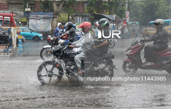 Commuters are crossing a road during heavy monsoon rain in Kolkata, eastern India, on July 30, 2024 