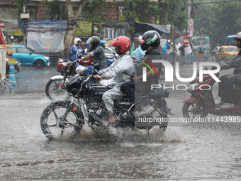 Commuters are crossing a road during heavy monsoon rain in Kolkata, eastern India, on July 30, 2024 (