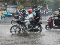 Commuters are crossing a road during heavy monsoon rain in Kolkata, eastern India, on July 30, 2024 (