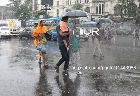 A family is crossing a road during monsoon rain in Kolkata, eastern India, on July 30, 2024 