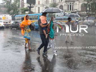 A family is crossing a road during monsoon rain in Kolkata, eastern India, on July 30, 2024 (