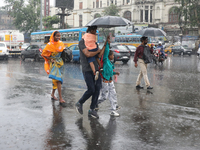 A family is crossing a road during monsoon rain in Kolkata, eastern India, on July 30, 2024 (