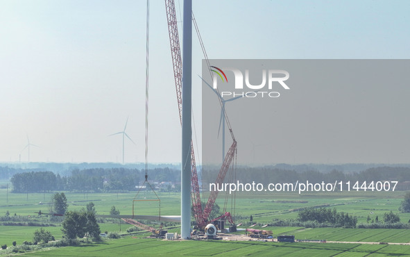 Workers are installing wind power equipment at Henggou village in Huai'an city, East China's Jiangsu province, on July 30, 2024. 