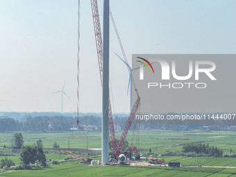 Workers are installing wind power equipment at Henggou village in Huai'an city, East China's Jiangsu province, on July 30, 2024. (