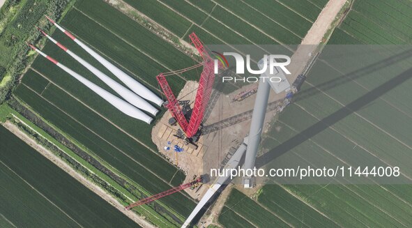 Workers are installing wind power equipment at Henggou village in Huai'an city, East China's Jiangsu province, on July 30, 2024. 