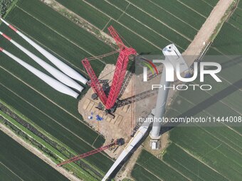 Workers are installing wind power equipment at Henggou village in Huai'an city, East China's Jiangsu province, on July 30, 2024. (