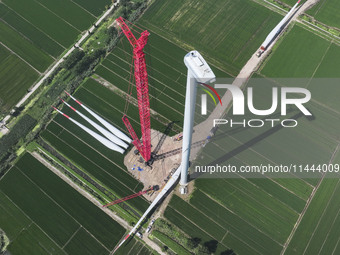 Workers are installing wind power equipment at Henggou village in Huai'an city, East China's Jiangsu province, on July 30, 2024. (