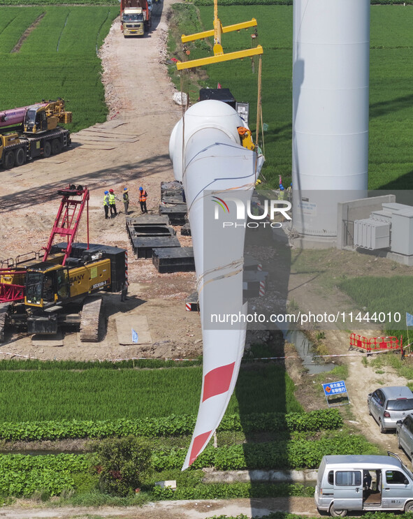 Workers are installing wind power equipment at Henggou village in Huai'an city, East China's Jiangsu province, on July 30, 2024. 