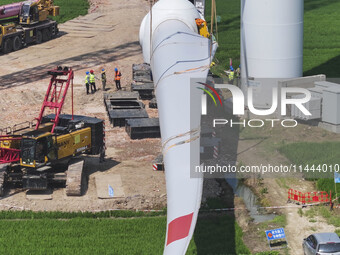 Workers are installing wind power equipment at Henggou village in Huai'an city, East China's Jiangsu province, on July 30, 2024. (