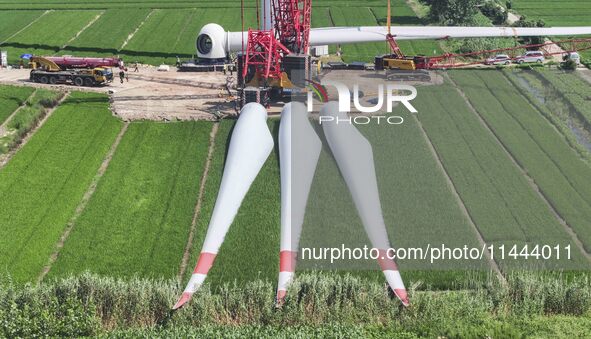 Workers are installing wind power equipment at Henggou village in Huai'an city, East China's Jiangsu province, on July 30, 2024. 