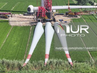 Workers are installing wind power equipment at Henggou village in Huai'an city, East China's Jiangsu province, on July 30, 2024. (