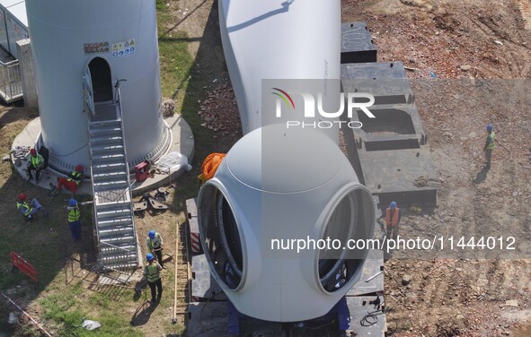 Workers are installing wind power equipment at Henggou village in Huai'an city, East China's Jiangsu province, on July 30, 2024. 