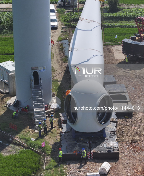 Workers are installing wind power equipment at Henggou village in Huai'an city, East China's Jiangsu province, on July 30, 2024. 