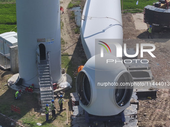 Workers are installing wind power equipment at Henggou village in Huai'an city, East China's Jiangsu province, on July 30, 2024. (