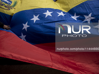 Opponents of Venezuelan President Nicolas Maduro are displaying a Venezuelan flag during a rally called by presidential candidate Edmundo Go...