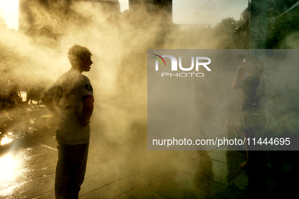 People are cooling off and enjoying a water spray as temperatures rise in Paris, France, on July 30, 2024, during the Paris 2024 Olympic Gam...