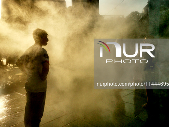 People are cooling off and enjoying a water spray as temperatures rise in Paris, France, on July 30, 2024, during the Paris 2024 Olympic Gam...