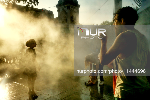 People are cooling off and enjoying a water spray as temperatures rise in Paris, France, on July 30, 2024, during the Paris 2024 Olympic Gam...