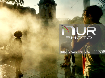 People are cooling off and enjoying a water spray as temperatures rise in Paris, France, on July 30, 2024, during the Paris 2024 Olympic Gam...