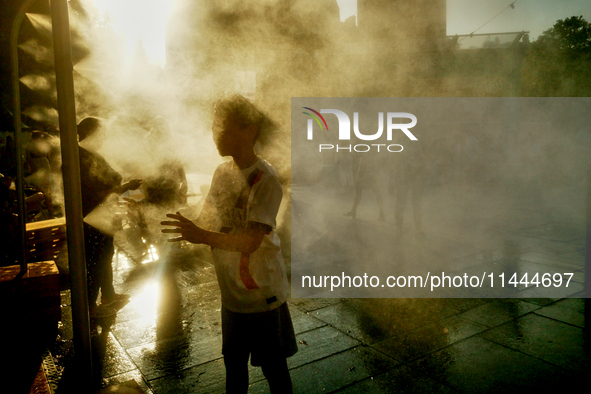 People are cooling off and enjoying a water spray as temperatures rise in Paris, France, on July 30, 2024, during the Paris 2024 Olympic Gam...