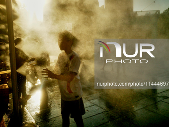 People are cooling off and enjoying a water spray as temperatures rise in Paris, France, on July 30, 2024, during the Paris 2024 Olympic Gam...