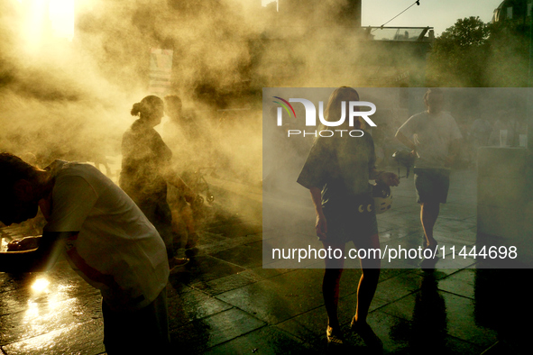 People are cooling off and enjoying a water spray as temperatures rise in Paris, France, on July 30, 2024, during the Paris 2024 Olympic Gam...