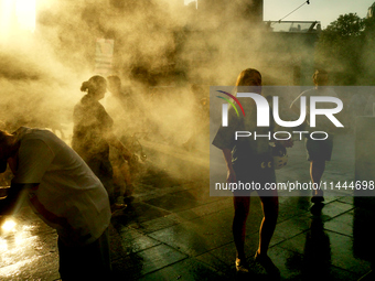 People are cooling off and enjoying a water spray as temperatures rise in Paris, France, on July 30, 2024, during the Paris 2024 Olympic Gam...