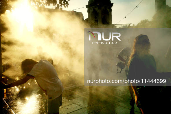 People are cooling off and enjoying a water spray as temperatures rise in Paris, France, on July 30, 2024, during the Paris 2024 Olympic Gam...