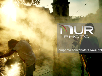 People are cooling off and enjoying a water spray as temperatures rise in Paris, France, on July 30, 2024, during the Paris 2024 Olympic Gam...