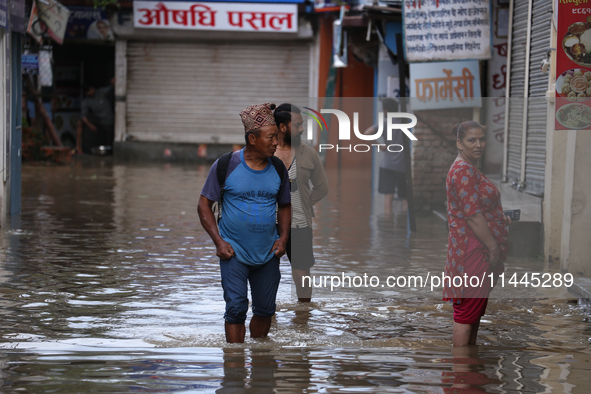 Residents of Kathmandu are wading through the floodwater along the embankment of the Bagmati River flowing through the capital after incessa...