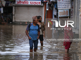 Residents of Kathmandu are wading through the floodwater along the embankment of the Bagmati River flowing through the capital after incessa...