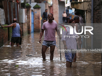 Residents of Kathmandu are wading through the floodwater along the embankment of the Bagmati River flowing through the capital after incessa...