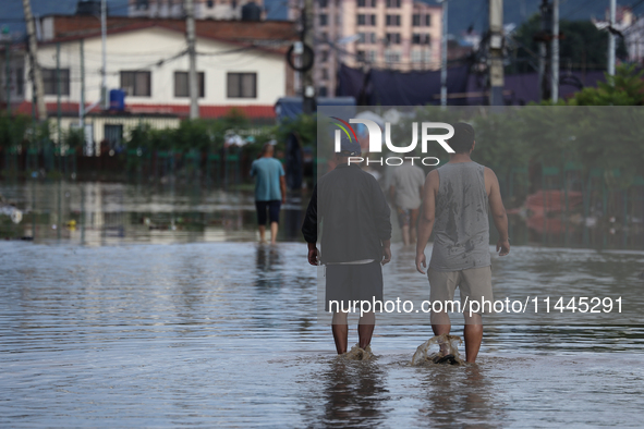 Residents of Kathmandu are wading through the floodwater along the embankment of the Bagmati River flowing through the capital after incessa...