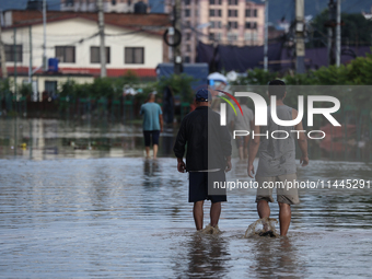 Residents of Kathmandu are wading through the floodwater along the embankment of the Bagmati River flowing through the capital after incessa...