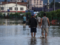 Residents of Kathmandu are wading through the floodwater along the embankment of the Bagmati River flowing through the capital after incessa...