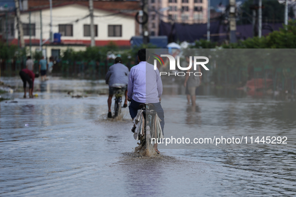 Residents of Kathmandu are wading through the floodwater along the embankment of the Bagmati River flowing through the capital after incessa...