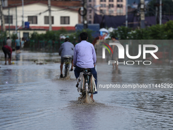 Residents of Kathmandu are wading through the floodwater along the embankment of the Bagmati River flowing through the capital after incessa...