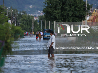 Residents of Kathmandu are wading through the floodwater along the embankment of the Bagmati River flowing through the capital after incessa...