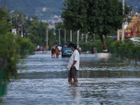 Residents of Kathmandu are wading through the floodwater along the embankment of the Bagmati River flowing through the capital after incessa...