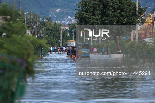 Residents of Kathmandu are wading through the floodwater along the embankment of the Bagmati River flowing through the capital after incessa...