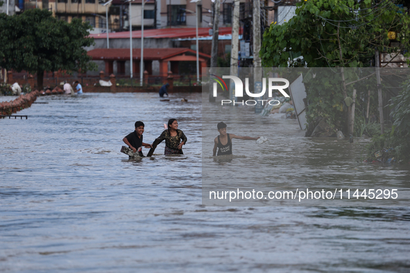 Residents of Kathmandu are wading through the floodwater along the embankment of the Bagmati River flowing through the capital after incessa...