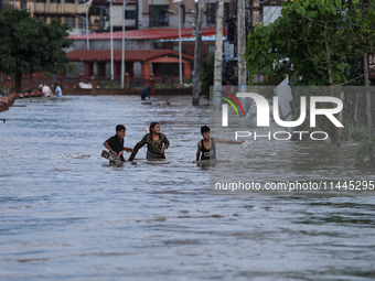 Residents of Kathmandu are wading through the floodwater along the embankment of the Bagmati River flowing through the capital after incessa...