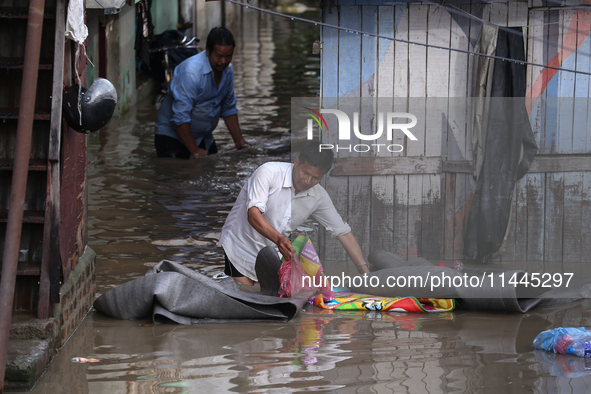 Residents of Kathmandu are wading through the floodwater along the embankment of the Bagmati River flowing through the capital after incessa...